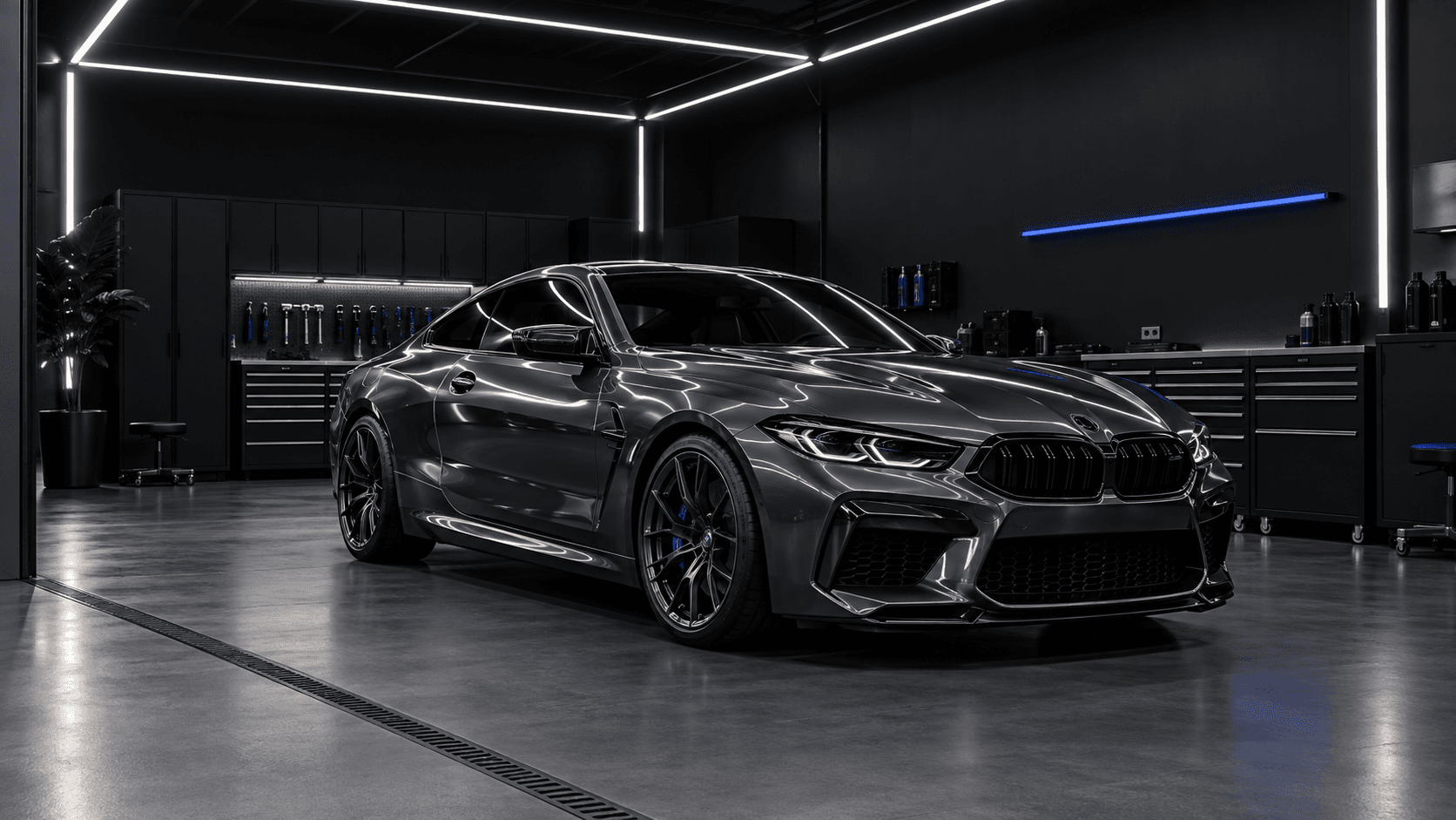 Dark one-bay detailing studio with a graphite coupe under soft light